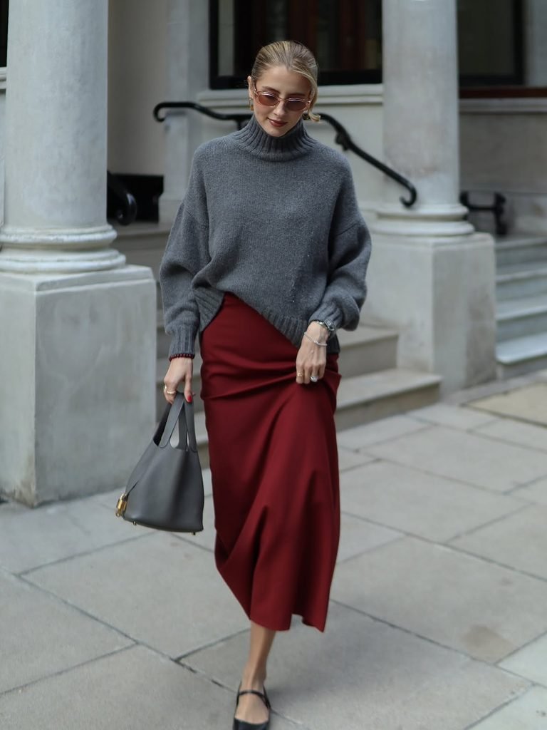 woman wearing grey turtleneck sweater, red maxi skirt, and black mary jane flats outdoors