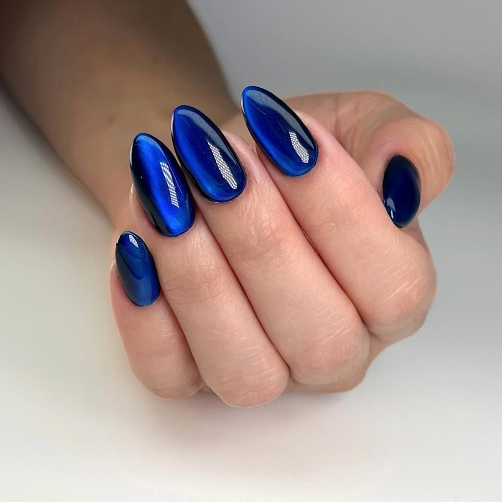 royal blue cat eye nails with a reflective metallic stripe on a manicured hand
