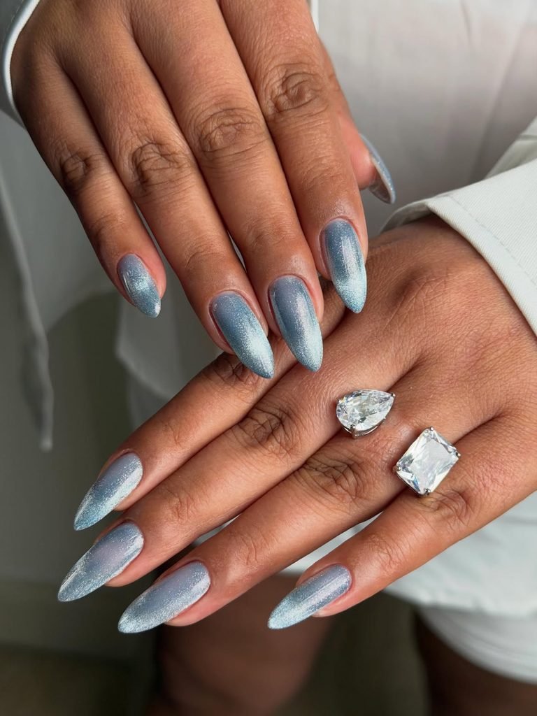 light blue cat eye nails on hands wearing two large diamond rings