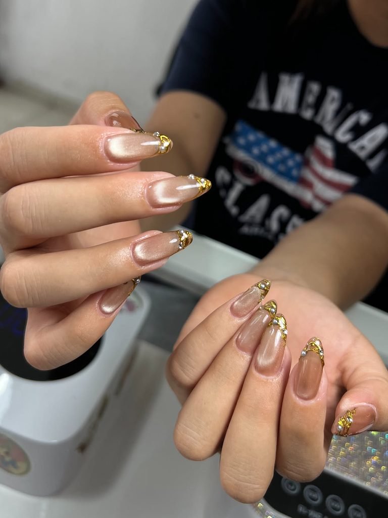 nude cat eye nails with elegant gold wire and pearl accents on the tips