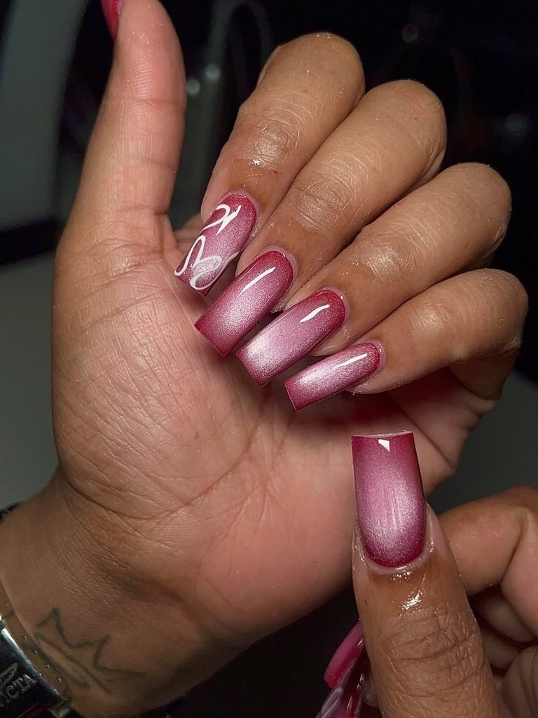 square pink cat eye nails with white line art on a manicured hand