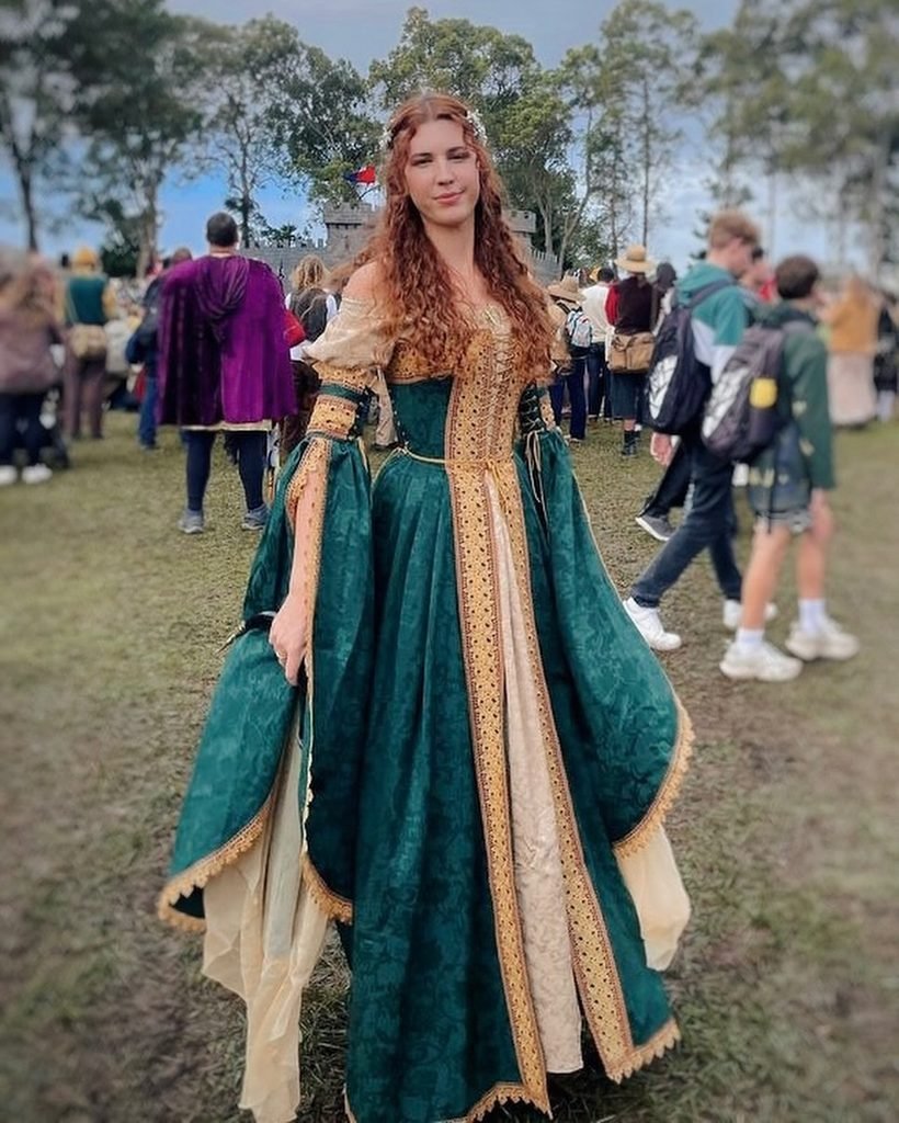 woman wearing a green and gold medieval renaissance dress at an outdoor festival