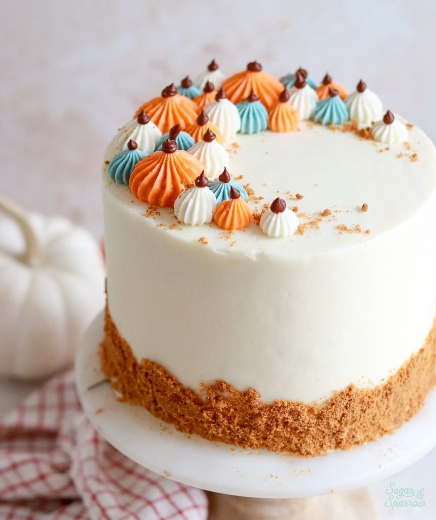 frosted pumpkin layer cake decorated with colorful piped buttercream pumpkins