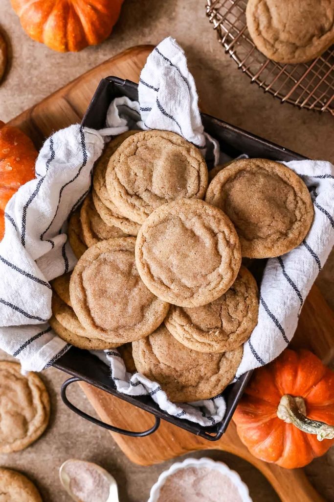 soft baked pumpkin spice cookies stacked inside a cloth-lined metal basket