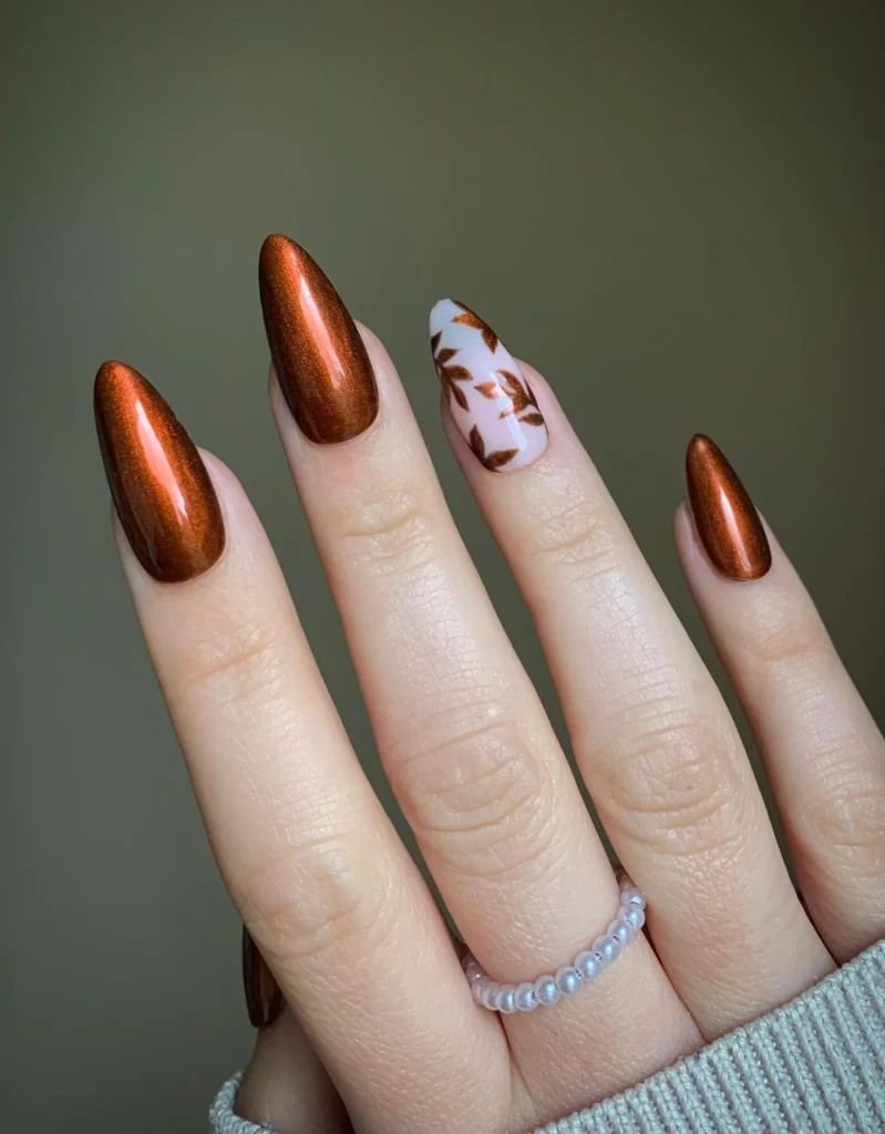 long almond nails with metallic copper polish and an autumn leaf accent design