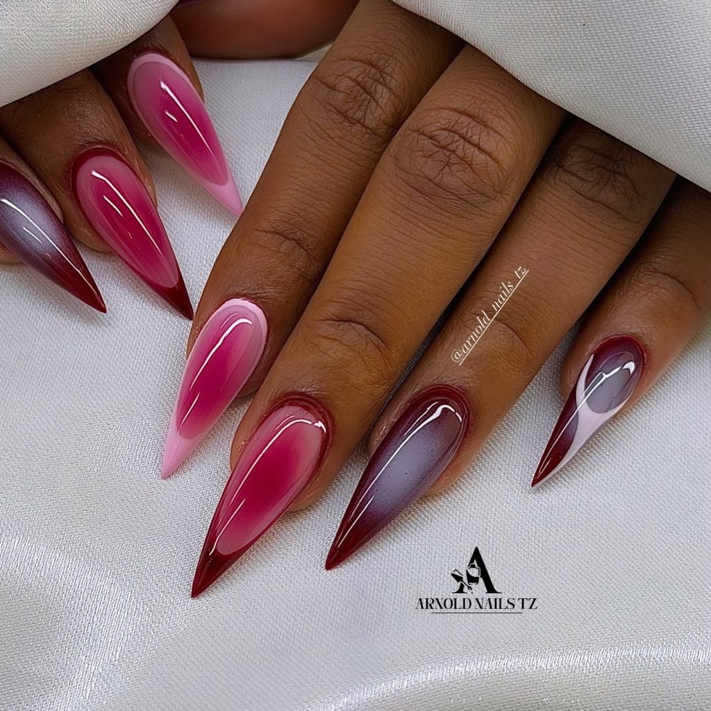 long stiletto nails with magenta and dark burgundy aura effects on a hand