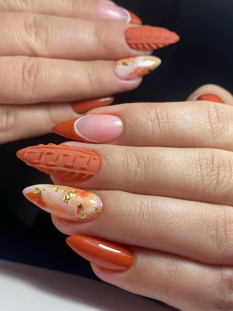 burnt orange almond nails featuring sweater texture art and gold foil details