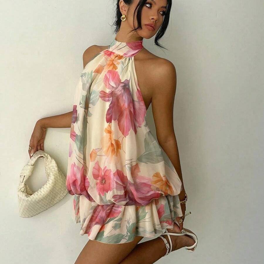 woman wearing a floral halter mini dress holding a woven white purse
