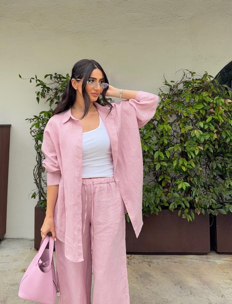 woman wearing an oversized pink linen shirt and matching pants set outside