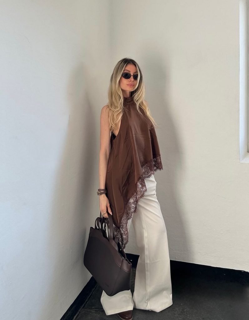 woman in a brown satin halter top and wide leg white pants