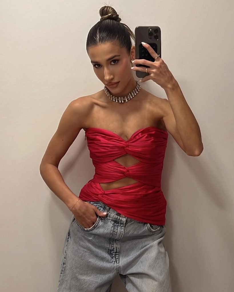 woman taking a selfie wearing a pink strapless ruched top and jeans