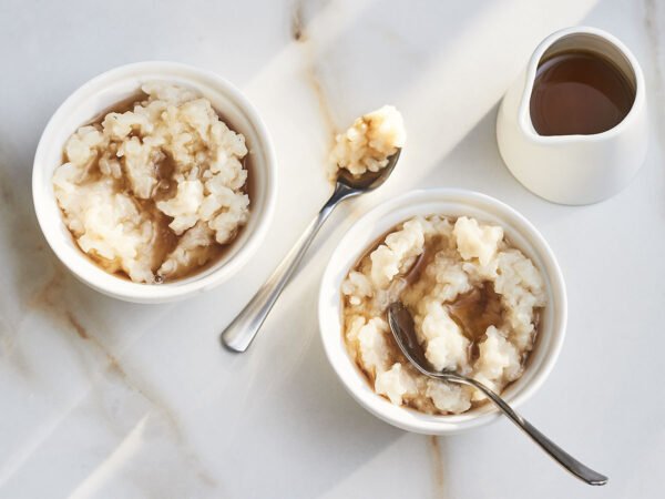 bowls of maple rice pudding served with spoons and syrup pitcher