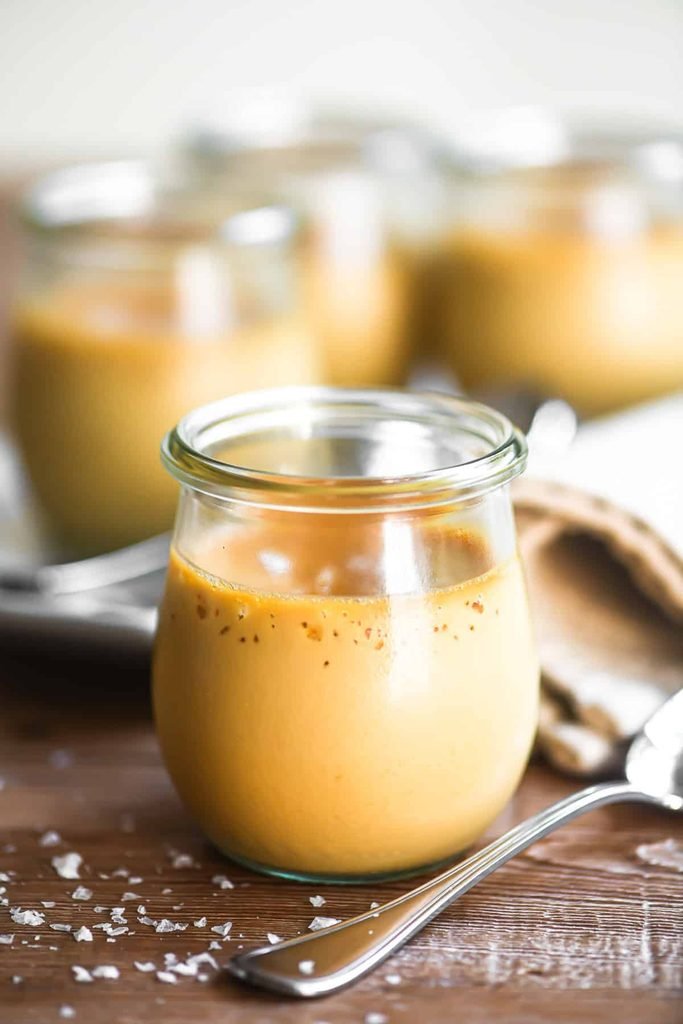 salted caramel pot de creme in small glass jar next to sea salt flakes