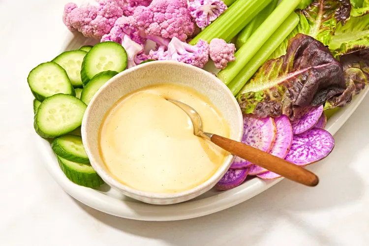 creamy mustard maple sauce in a small bowl surrounded by fresh colorful sliced vegetables