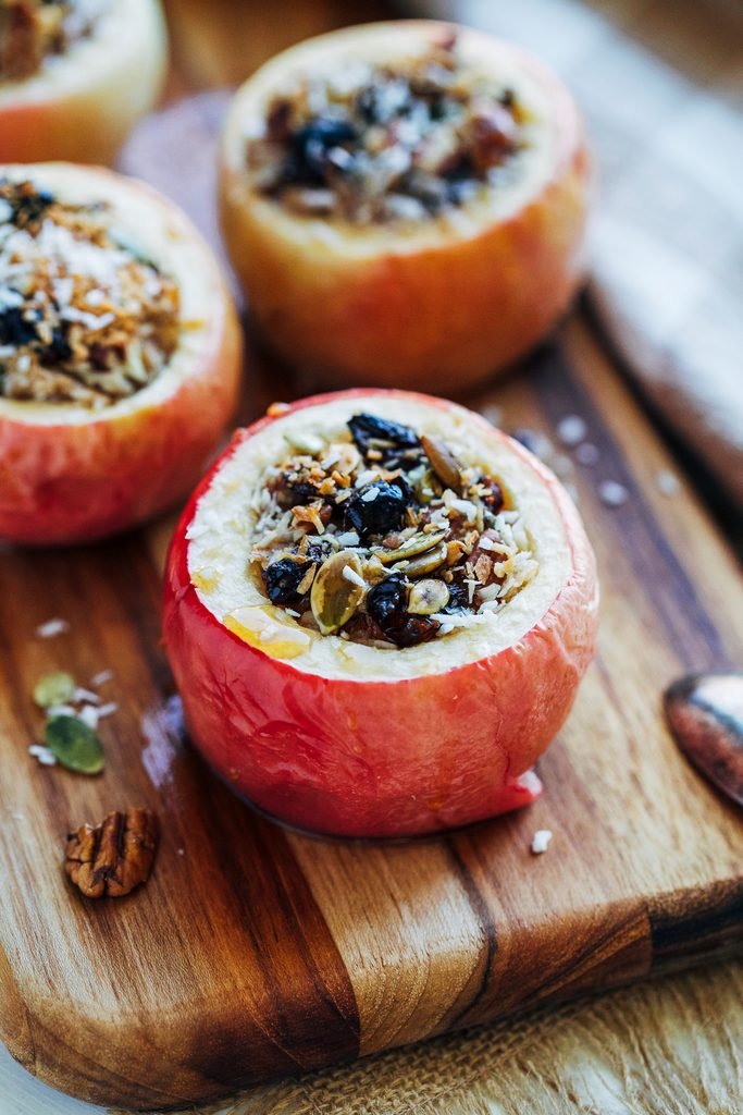 baked apples stuffed with almond butter, nuts, and seeds on a wooden board