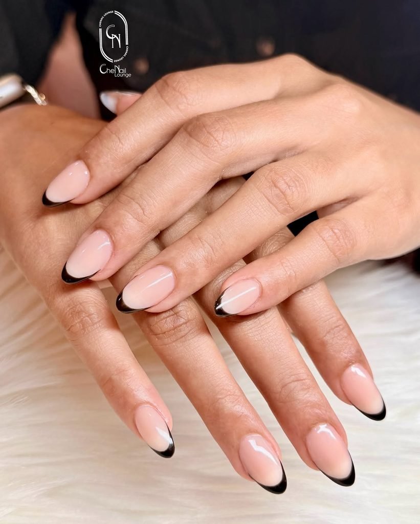 almond manicured nails with thin black french tips on nude base