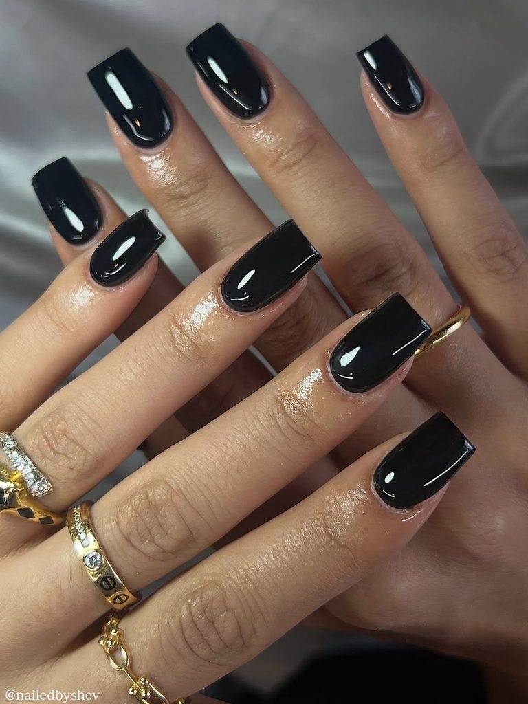 glossy black square manicured nails with gold rings on fingers
