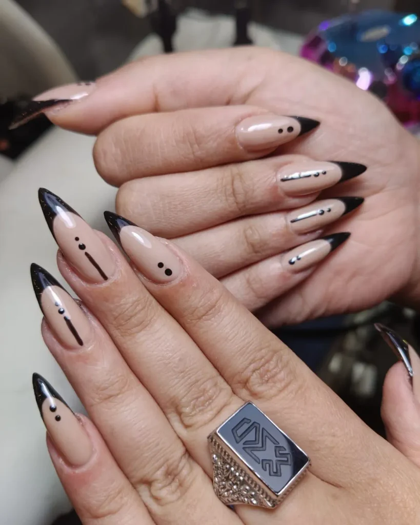 long stiletto manicured nails with nude base black french tips and minimalist dots