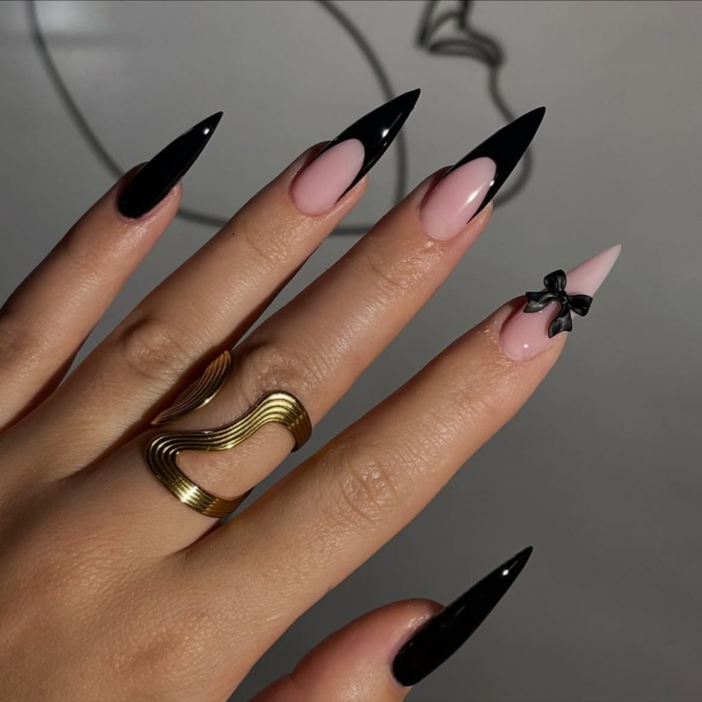long stiletto manicured nails with black french tips and tiny bow