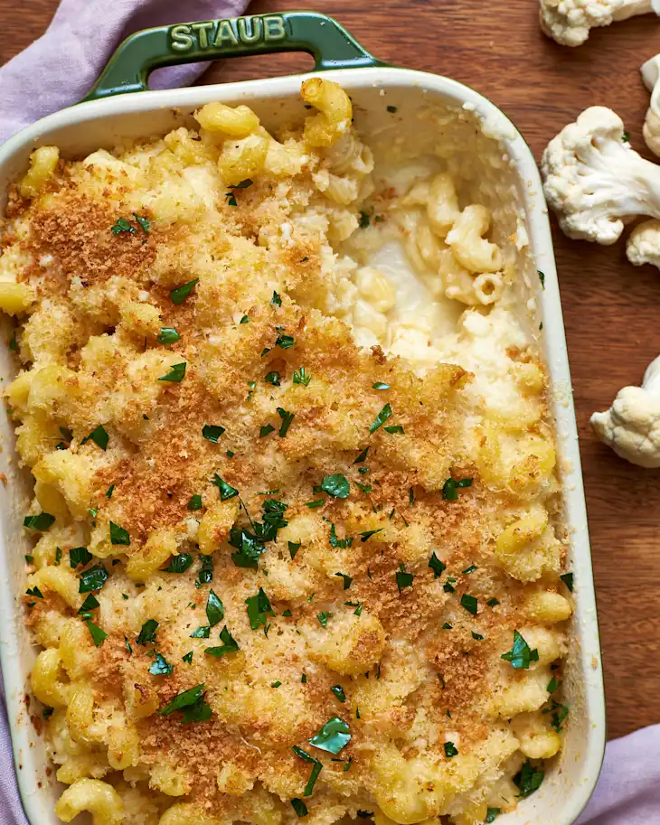 baked cauliflower mac and cheese topped with breadcrumbs in a ceramic casserole dish