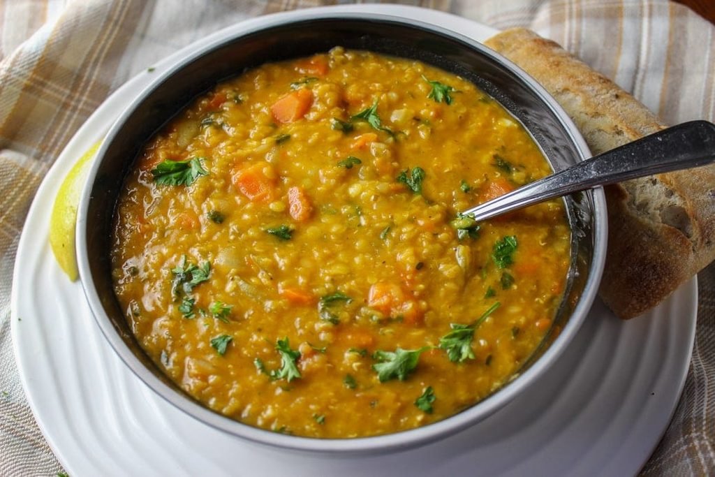 yellow lentil vegetable soup topped with fresh herbs and served with crusty bread