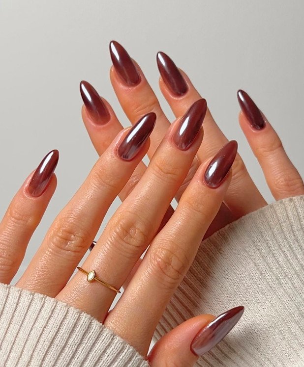shiny metallic copper brown almond nails worn with a simple gold ring