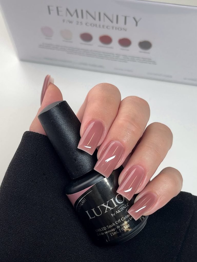 glossy muted pinkish mauve square nails holding a nail polish bottle