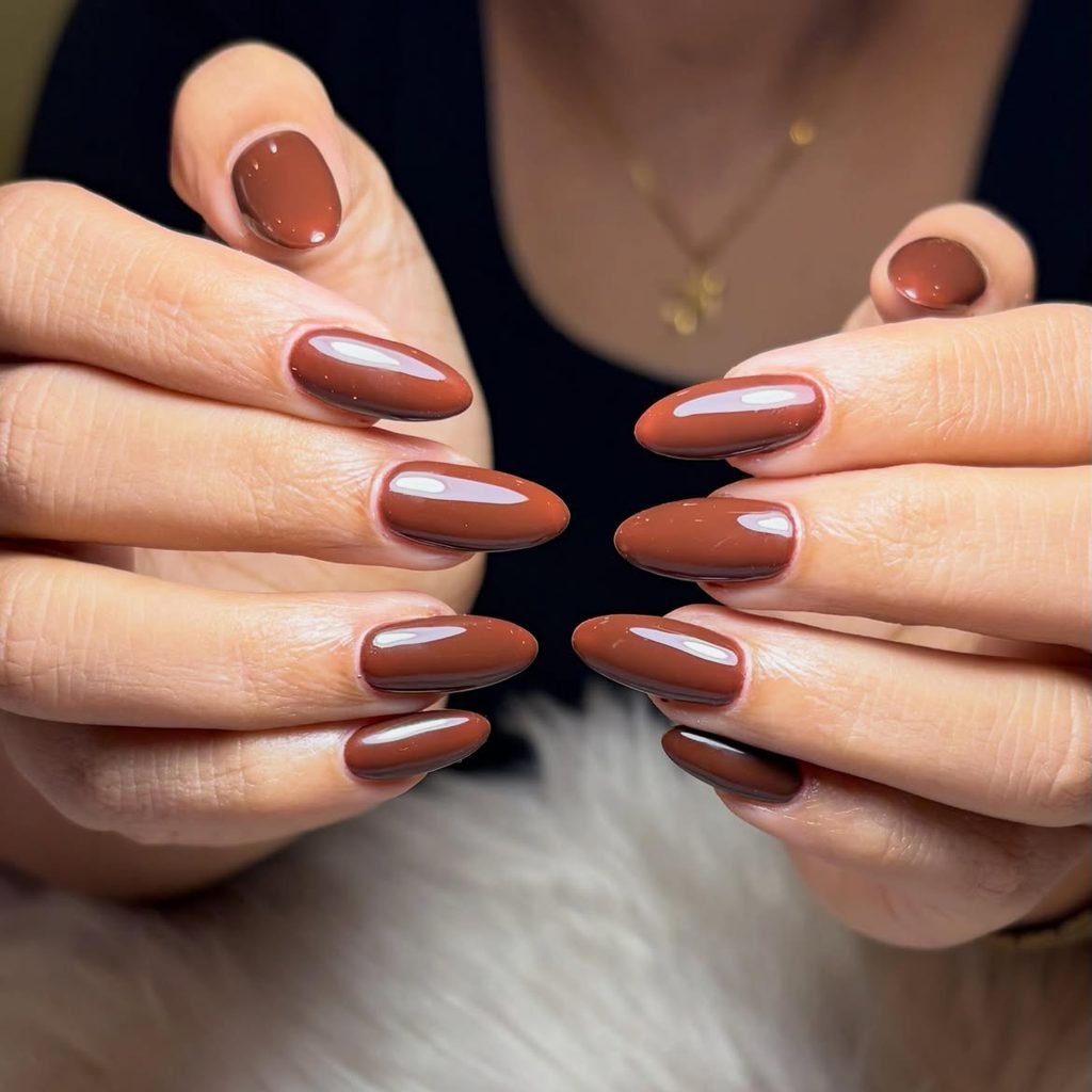 glossy dark chocolate brown oval manicured nails on hands resting together