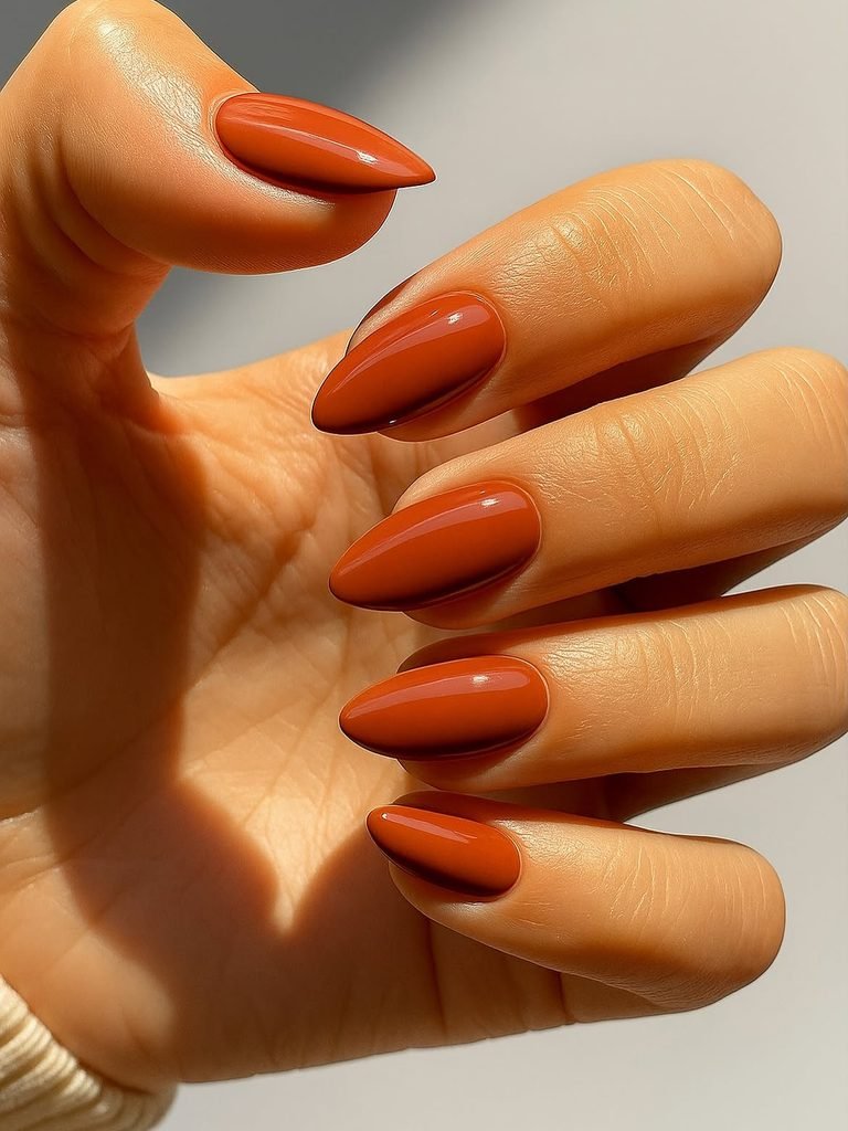 glossy terracotta orange almond nails glowing in natural warm sunlight