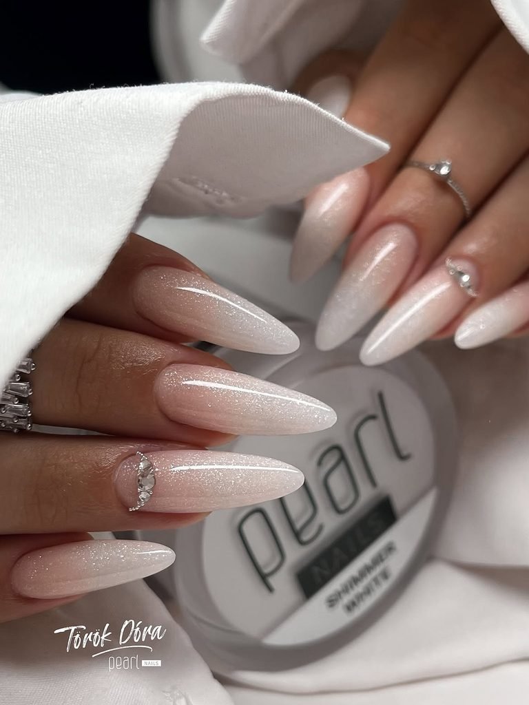 shimmer white almond nails featuring subtle glitter ombre and delicate rhinestone cuticle accents
