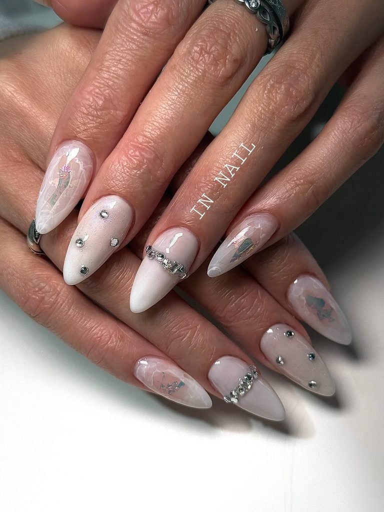 milky white stiletto nails with delicate quartz marbling rhinestone studs and silver chains