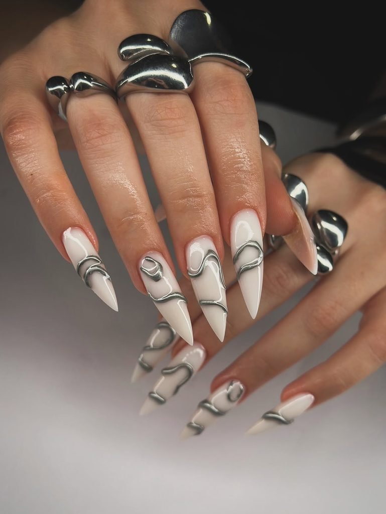 long white stiletto nails adorned with 3d silver chrome swirl accents