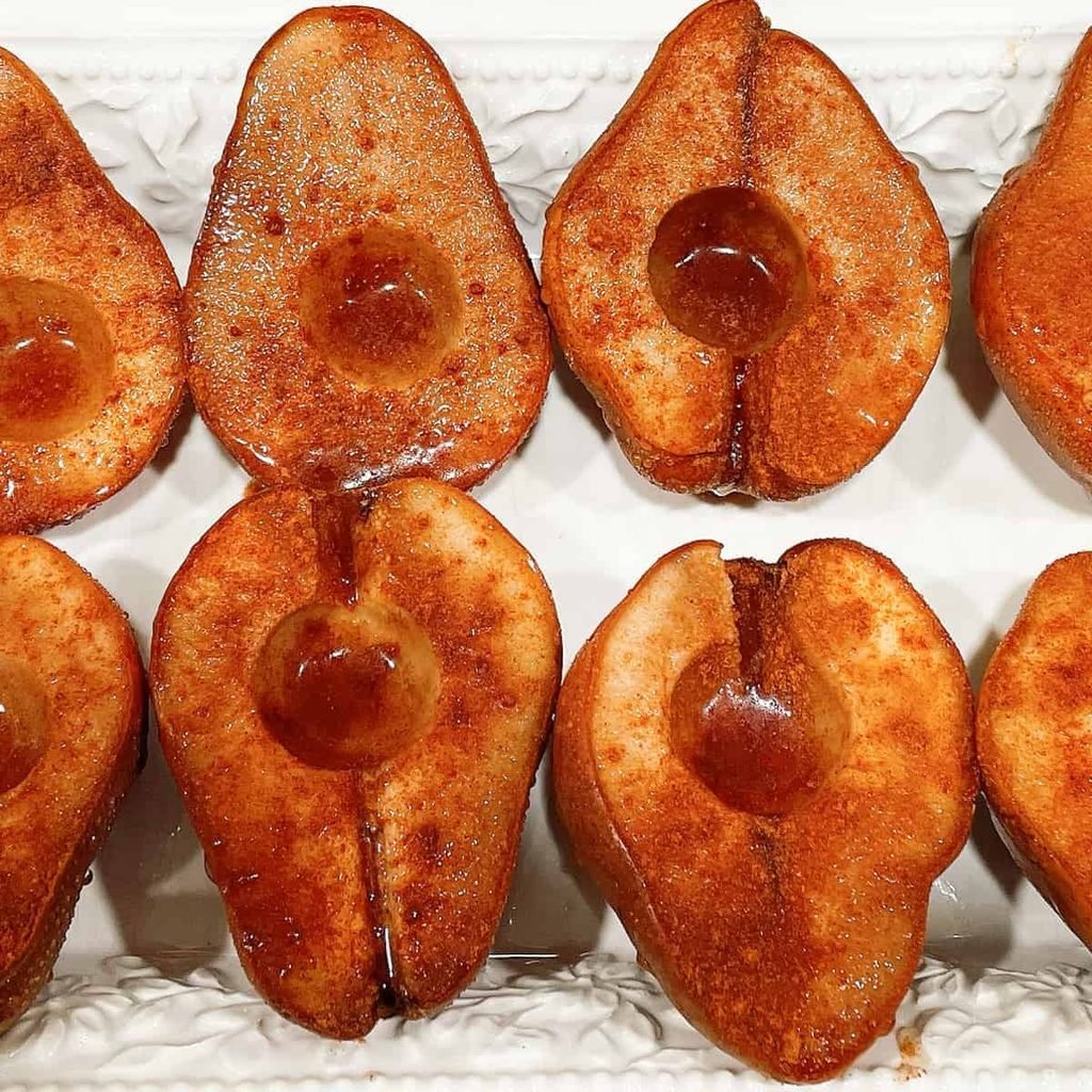 cinnamon baked pear halves arranged neatly on a white ceramic serving tray