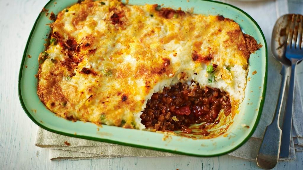 lentil shepherd's pie baked with golden mashed potato crust in a green dish