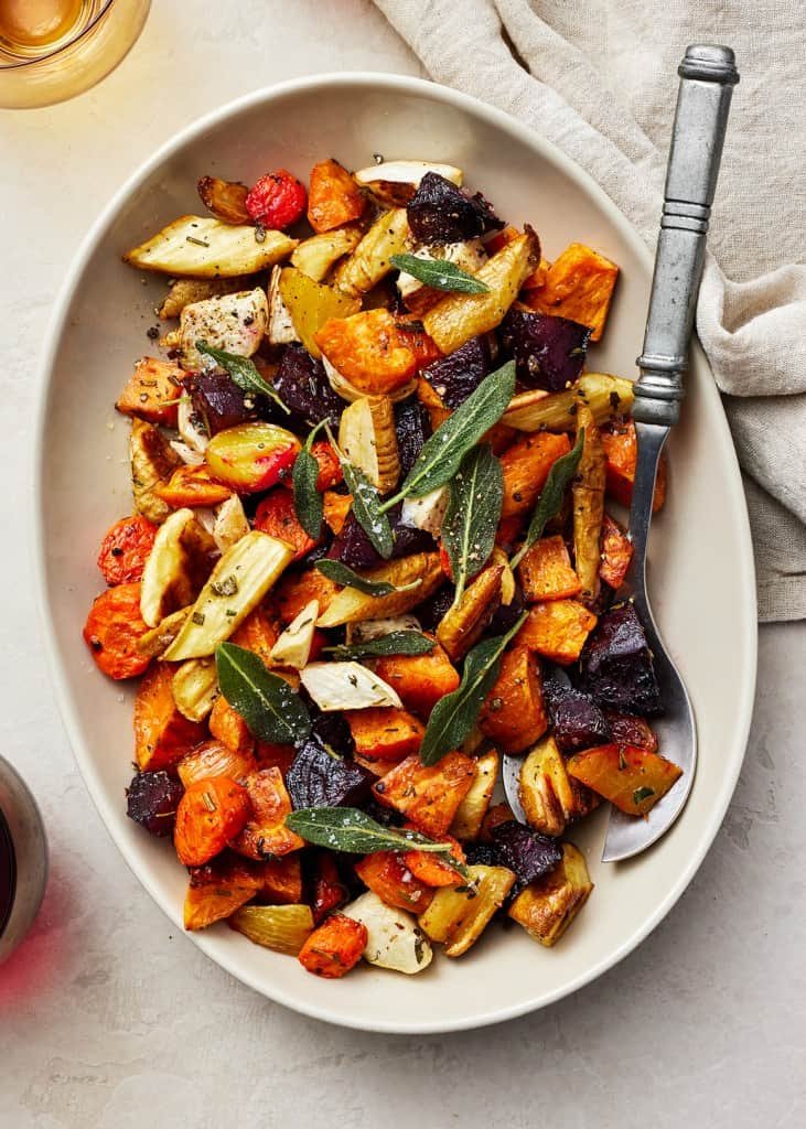 roasted root vegetables featuring carrots, beets, and sweet potatoes garnished with fresh sage leaves