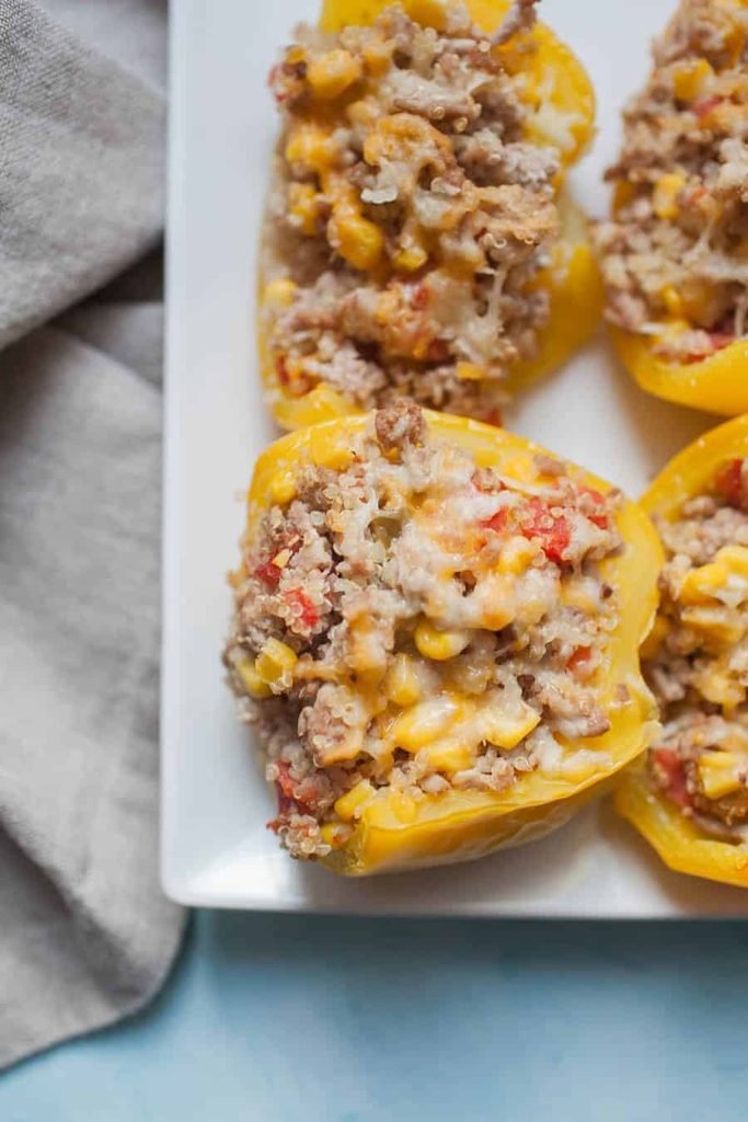 turkey and quinoa stuffed yellow bell peppers topped with melted cheese closeup