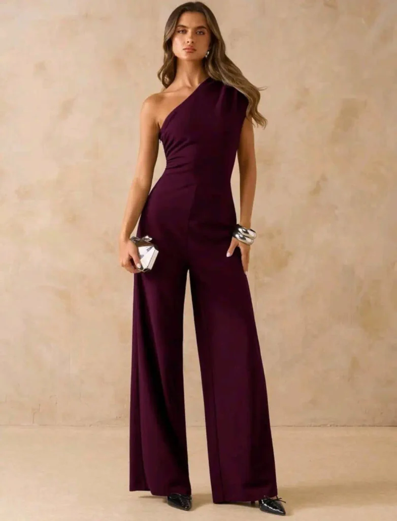 woman wearing a plum purple one shoulder wide leg jumpsuit with silver accessories