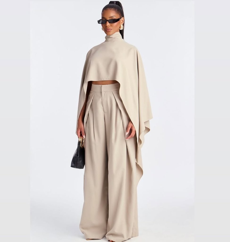 woman wearing a beige high neck cape top paired with matching wide leg trousers