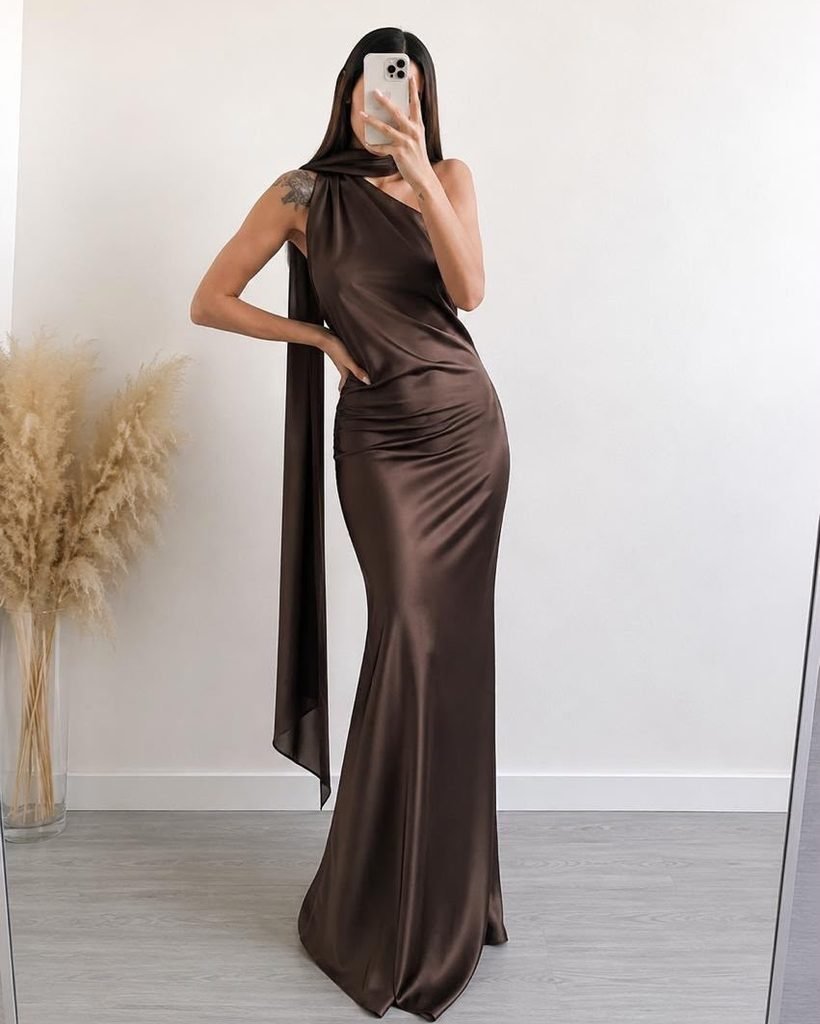woman wearing a dark brown silk one shoulder gown with a draped scarf