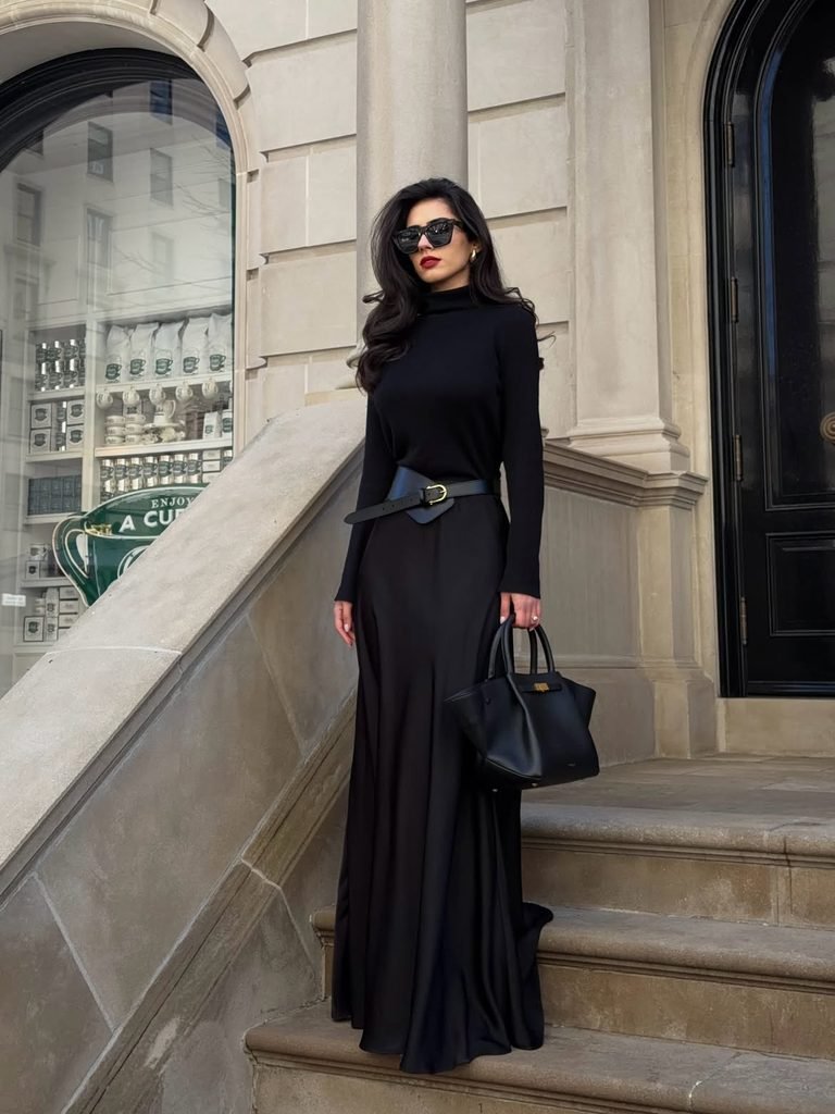 woman wearing a long black turtleneck dress paired with a wide leather belt