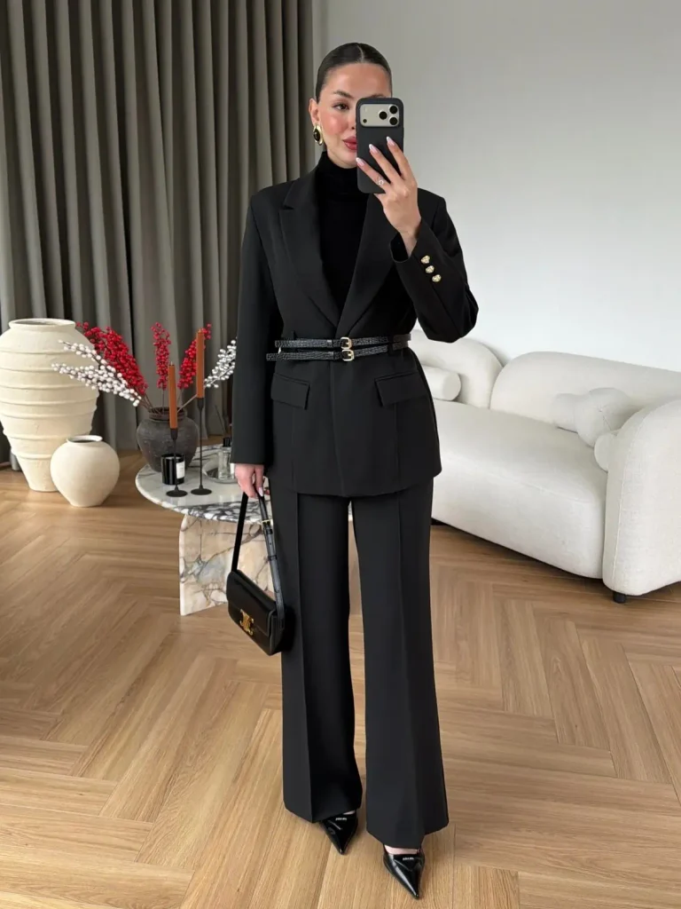 woman wearing a tailored black pantsuit cinched with a double buckled belt