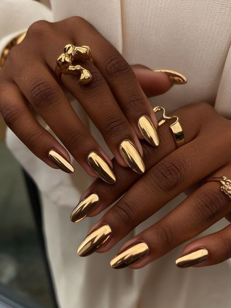 mirror shine metallic gold chrome almond nails on dark skin with rings