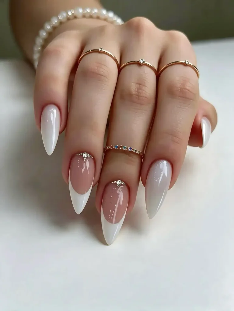 white french manicure stiletto nails with small crystal embellishments at the base