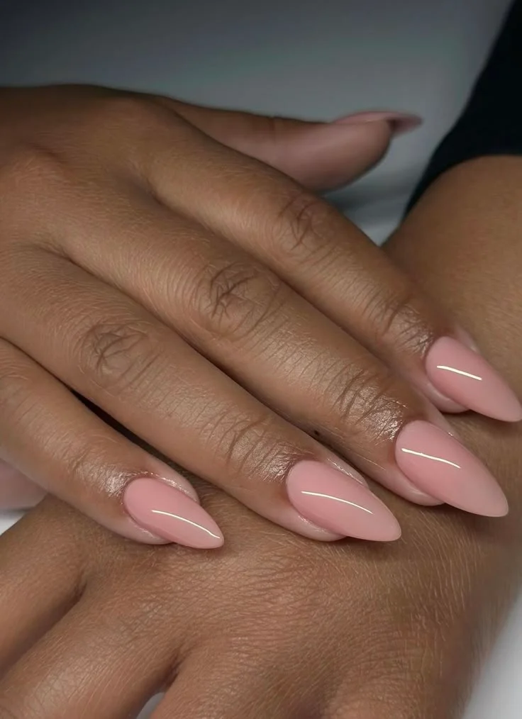 glossy light pink glossy nude almond nails on dark skin