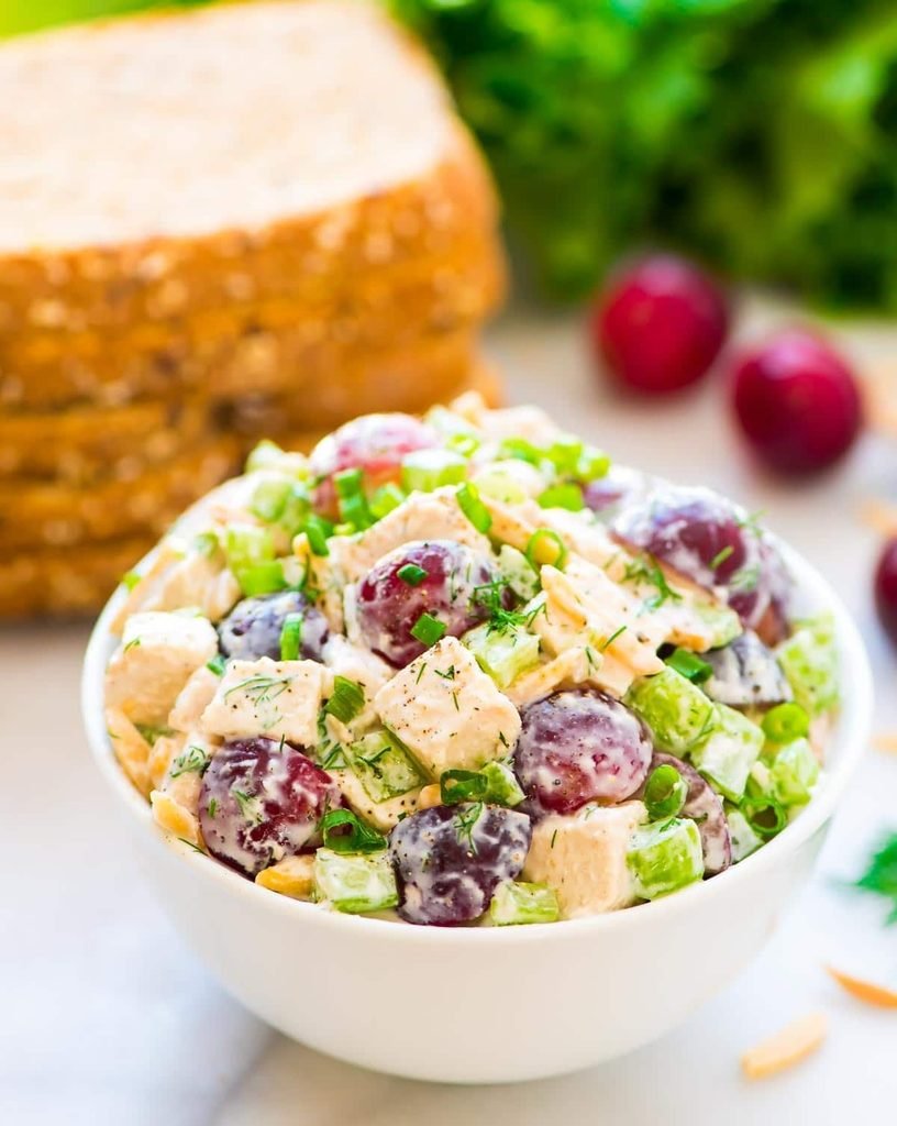 white bowl filled with greek yogurt chicken salad with grapes, celery, and green onions