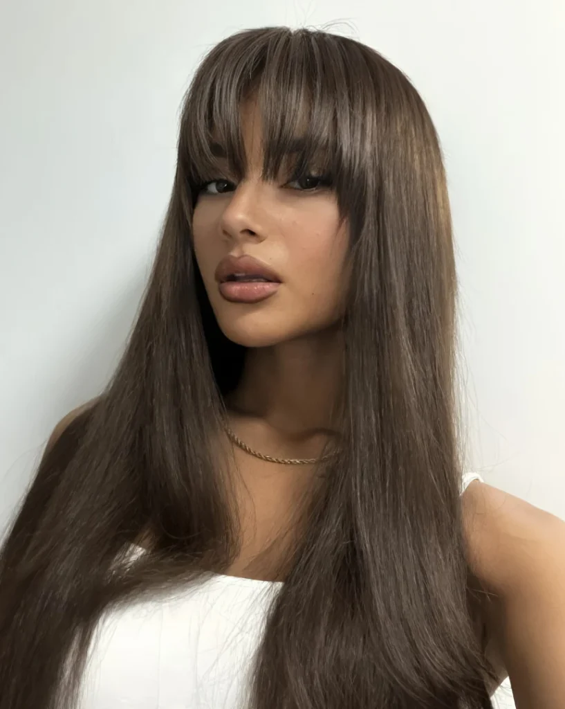 long brunette haircut with full bangs and sleek straight layers