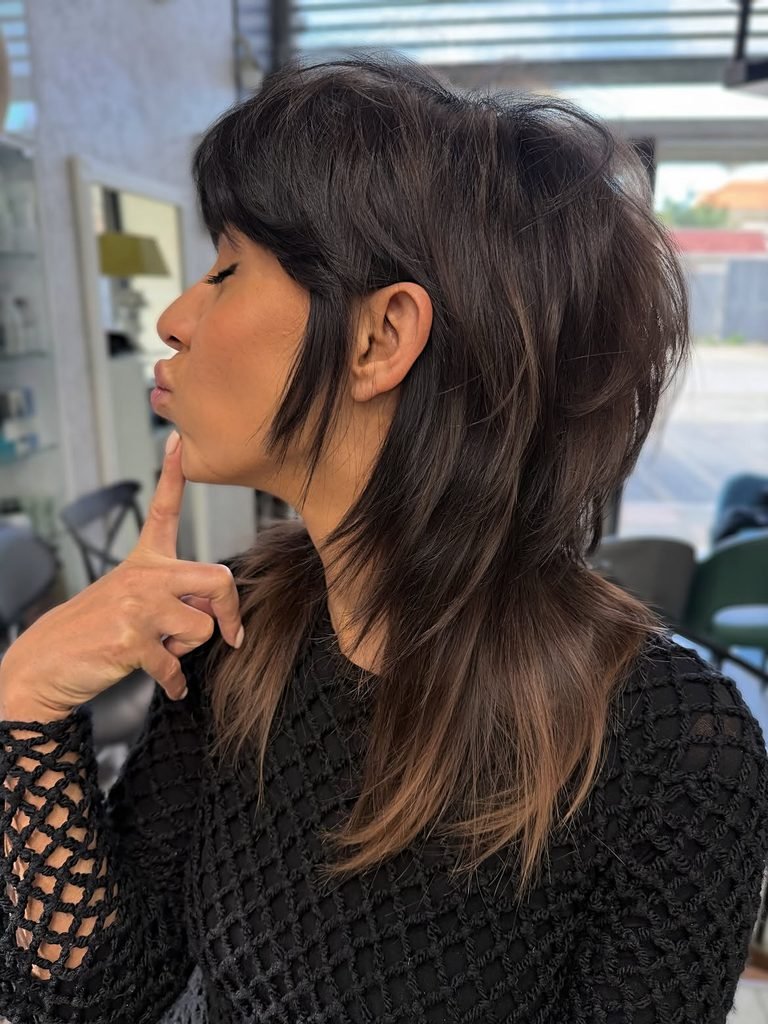 medium length brunette haircut with wispy bangs and textured layered ends