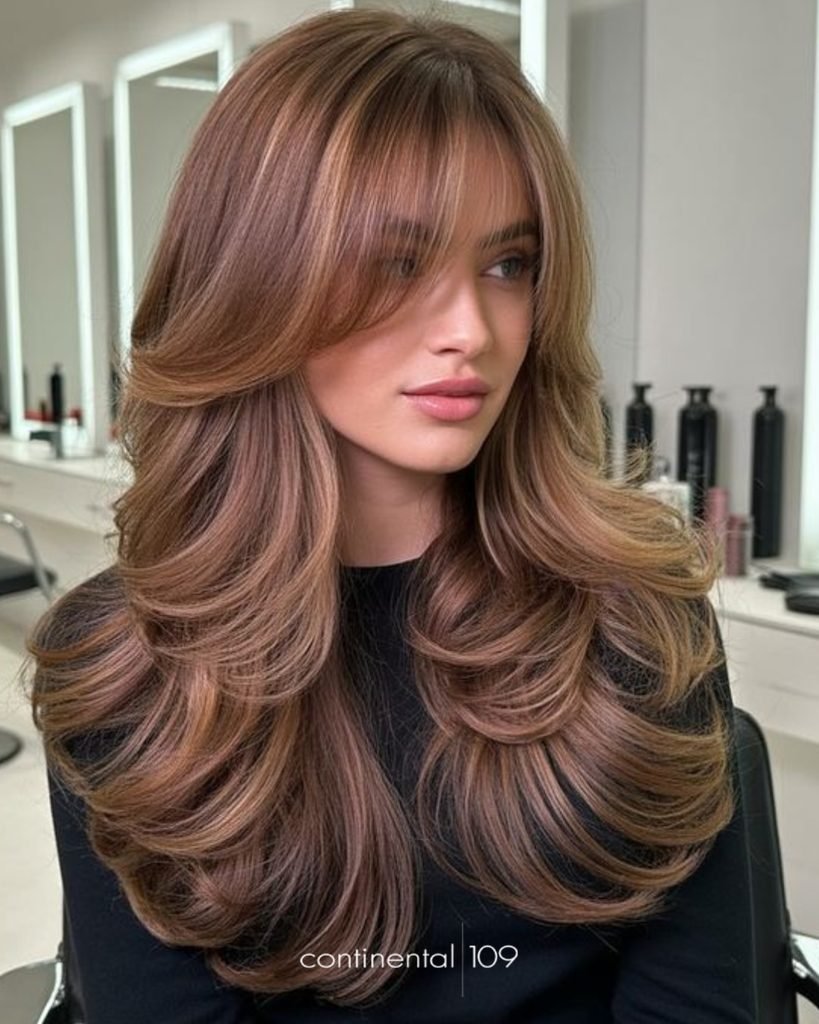 long layered brown haircut with voluminous feathered waves and curtain bangs