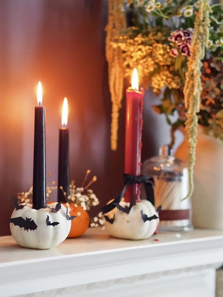 halloween mantle decor with black and red taper candles in mini pumpkins