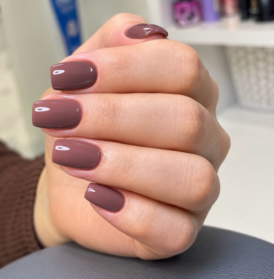 glossy dusty rose square nails on a hand with a manicured finish   